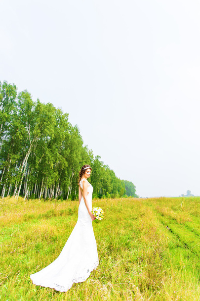 Belle mariée avec bouquet de mariage de fleurs en plein air dans le champ
 - Photo, image