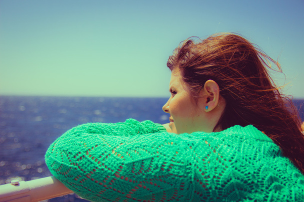Nainen nojaa kaiteeseen ja katselee merelle horisontissa
 - Valokuva, kuva