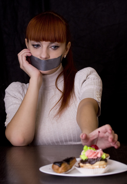 The girl, whose mouth sealed with tape sad looking at plate with - Фото, зображення