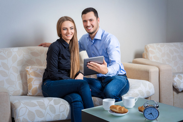 Joven hombre y mujer en el sofá con tableta electrónica
 - Foto, imagen