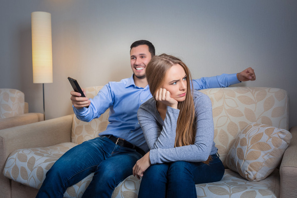 Portrait of couple sitting on sofa watching television. - Foto, imagen