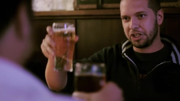 Two men toasting beer in a pub - Materiał filmowy, wideo