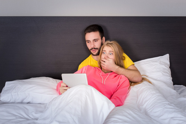 junges süßes Paar im Bett beobachtet etwas auf Tablet-Gadget - Foto, Bild