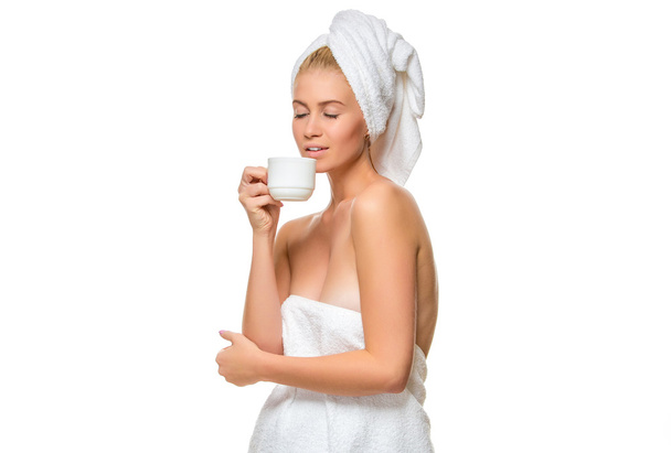 Jonge vrouw in de handdoek drinkt uit een kopje - Foto, afbeelding