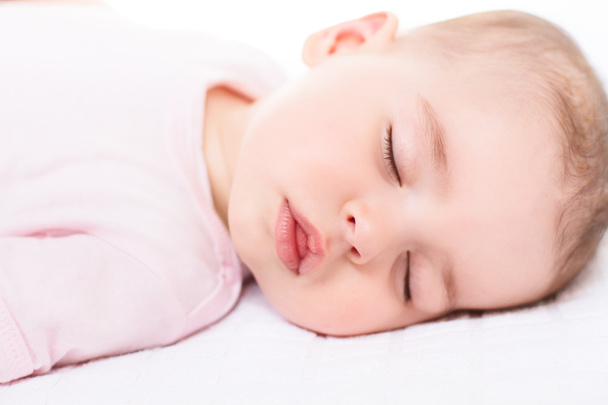 Adorable close-up portrait of sleeping cute baby girl on white bed - Valokuva, kuva