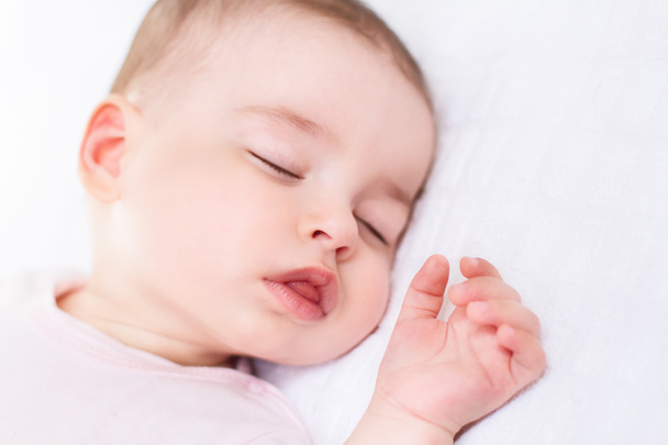 Amazing portrait of baby girl sleeping on pink suit and white bed - Foto, Imagem