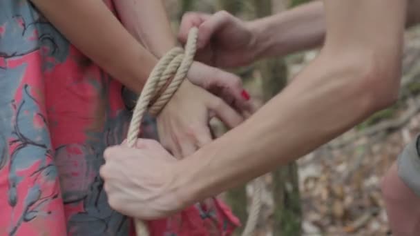 Las manos de un hombre atan las muñecas de una mujer con una cuerda
 - Imágenes, Vídeo