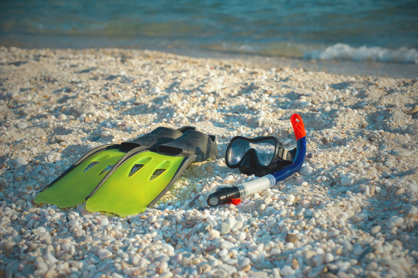 Mascarilla, snorkel y aletas para hacer snorkel en una playa de arena
. - Foto, Imagen