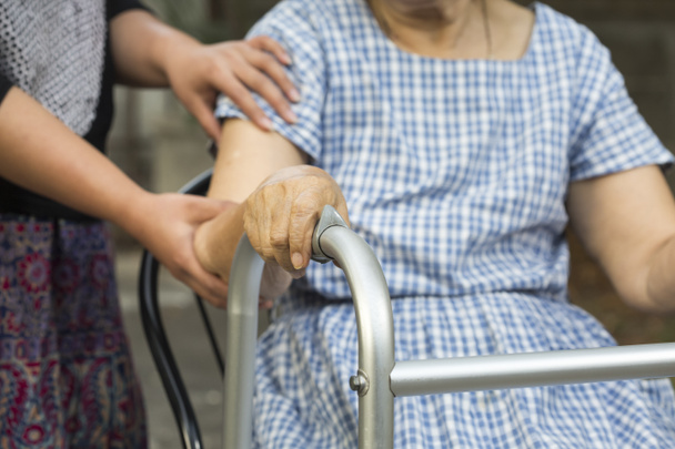 Seniorin sitzt mit Rollator bei Pflegekraft - Foto, Bild