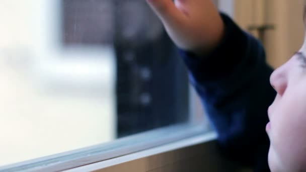 mietteliäs lapsi höyrystää ikkunan lasia hengityksellä
 - Materiaali, video