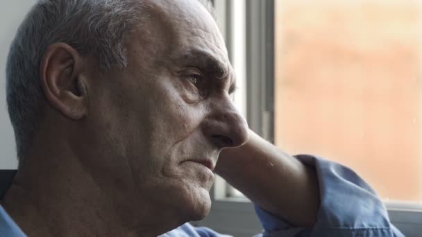 old man with troubles stays alone looking out of the window: sadness, depression - Filmati, video