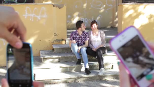 kaksi rakastavaiset ottavat kuvia ystäviltä - matkapuhelin - suudella - kuva
 - Materiaali, video