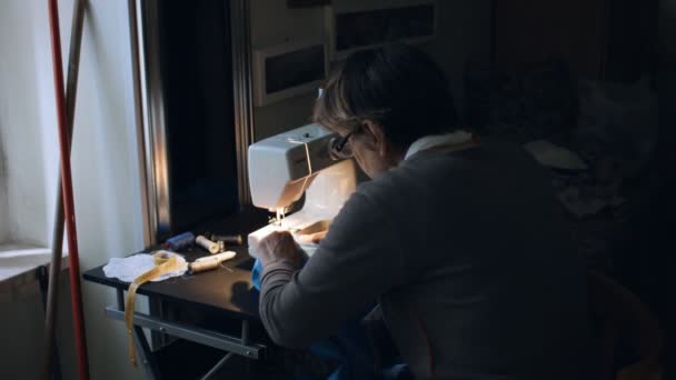 senior woman working at sewing machine at home - Séquence, vidéo