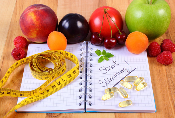 Frutas, suplementos de tabletas y centímetros con cuaderno, adelgazamiento y alimentos saludables
 - Foto, imagen