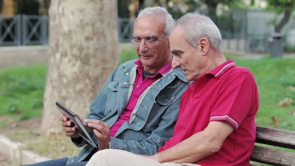Old man teaching his elderly friends to use a new tablet PC - Filmati, video