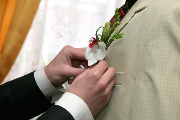 cada um ajuda a colocar a flor no terno para o noivo
  - Foto, Imagem