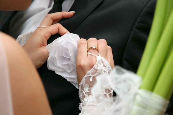невеста помогает жениху носить свадебный цветок на костюме
 - Фото, изображение