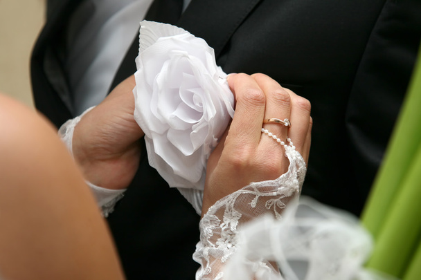 νύφη βοηθά να φορέσει ένα λουλούδι γάμο στο κοστούμι γαμπρού - Φωτογραφία, εικόνα