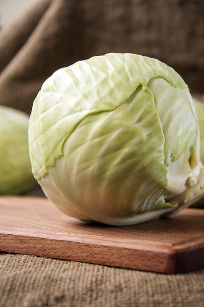 cabbage on a wooden board on a background sacking, burlap  - Фото, изображение