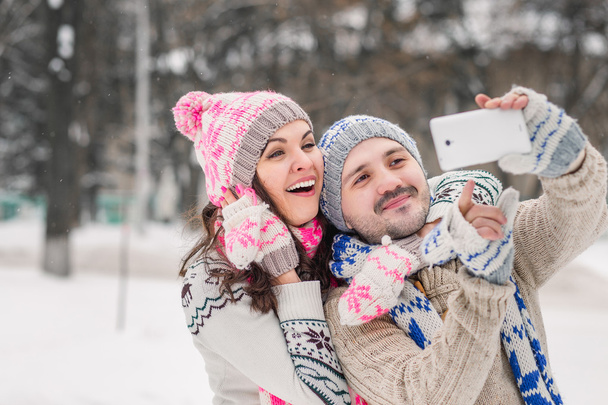 Verliebtes Paar lächelt und macht Selfie im Winter im Freien - Foto, Bild