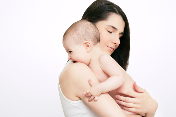Beautiful mom with closed eyes holding baby  on white background - Foto, imagen