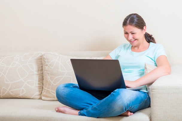 happy girl communicates online while sitting on a sofa - Foto, imagen