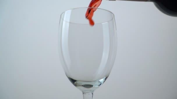 Kaatamalla punaviiniä lasiin valkoisella taustalla. Hidastus
 - Materiaali, video
