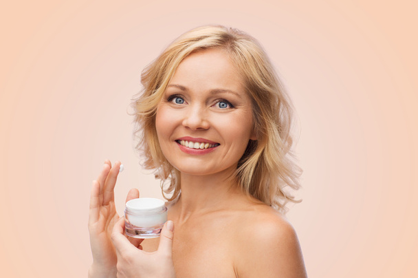 happy woman applying cream to her face - Photo, Image