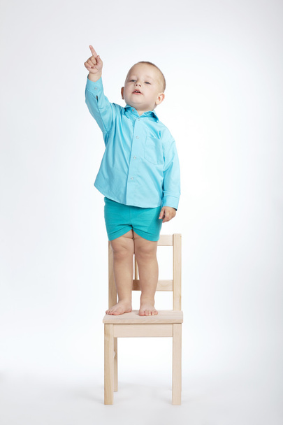 boy on chair and pointing his finger up - Фото, изображение