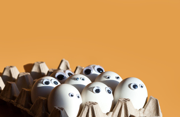 Group of eggs with false eyes in a cardboard container - Foto, Imagen