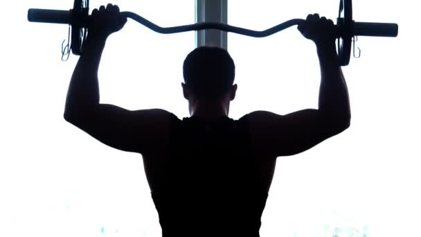 Silhouette, of athlete lifts barbell in gym - Footage, Video