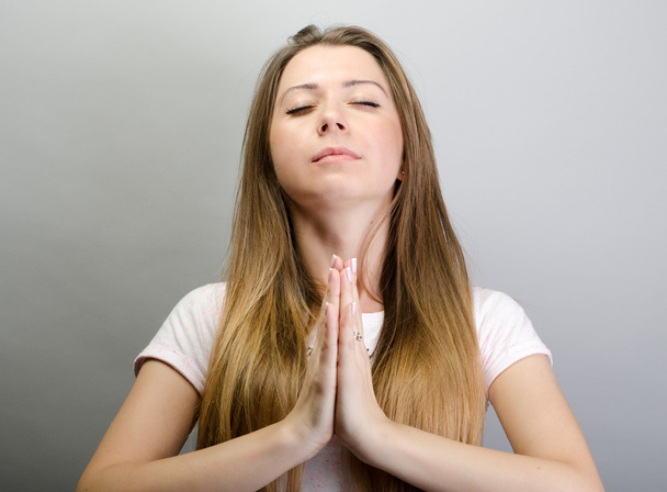 Κοντινό πορτραίτο μιας νεαρής γυναίκας που προσεύχεται - Φωτογραφία, εικόνα
