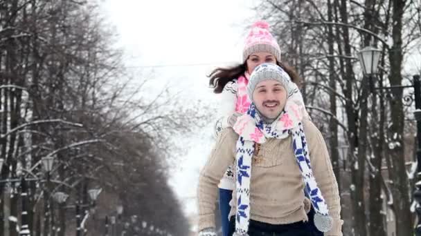 Paar genießt sein Winterwochenende zusammen, Kerl hält seine Freundin huckepack - Filmmaterial, Video
