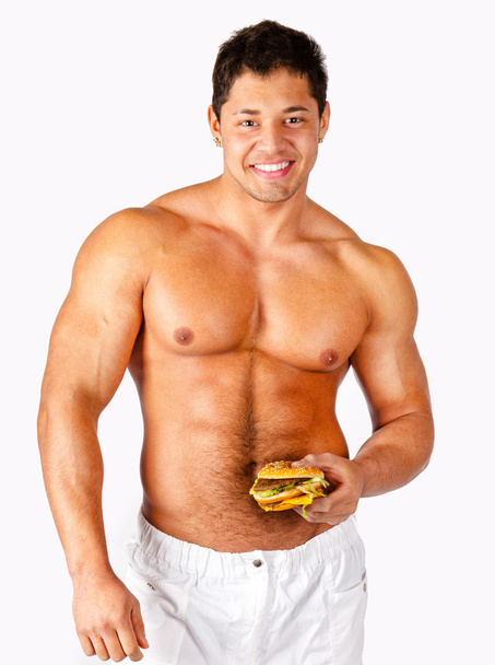 jovem muscular homem segurando um hambúrguer
 - Foto, Imagem