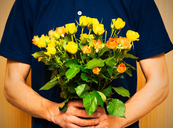 Mann mit einem Strauß gelber und orangefarbener Rosen. Frauentag, va - Foto, Bild