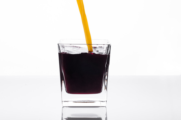 Orange juice pouring into glass with blackcurrant juice - Fotoğraf, Görsel