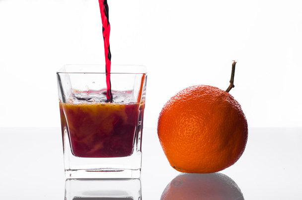 blackcurrant juice pouring into glass with orange juice - Fotó, kép