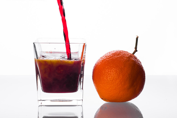 blackcurrant juice pouring into glass with orange juice - Fotó, kép