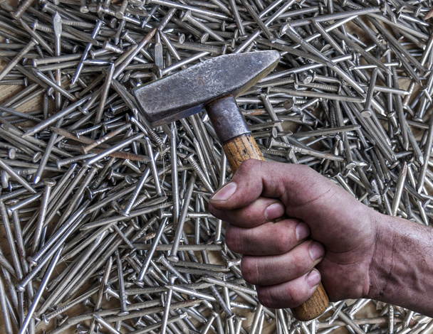 Man's hand holding hammer isolated on nail background - Foto, Bild