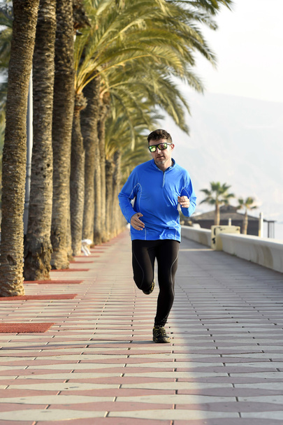 Sport człowiek biegnie wzdłuż plaży Palma drzewa boulevard w sesji szkoleniowej jogging rano - Zdjęcie, obraz