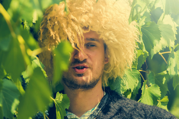 Porträt eines Mannes mit traditionellem Filzmantel und Pelzmütze im Freien im Weingarten  - Foto, Bild