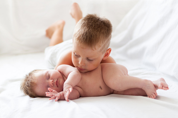 Первая любовь. Маленький мальчик смотрит на свою новорожденную сестру в помещении
 - Фото, изображение