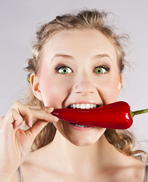 Beautiful woman teeth eating red hot chili pepper - Foto, afbeelding