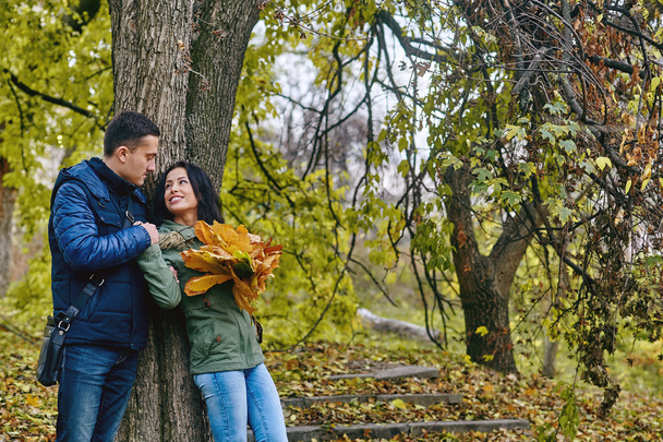 любовь, отношения, семья и люди - улыбающаяся пара обнимается в осеннем парке - Фото, изображение