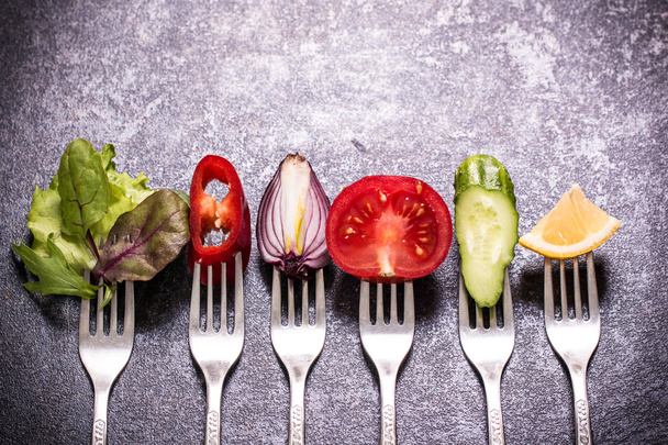 Fresh mixed vegetables on fork on black background - Фото, изображение