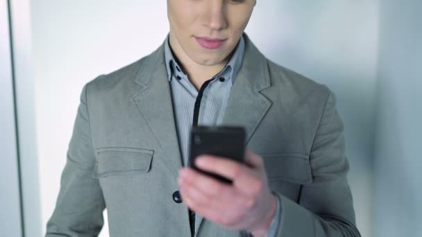 Handsome boy looks at phone - Materiał filmowy, wideo