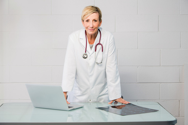 Ärztin steht hinter Schreibtisch - Foto, Bild
