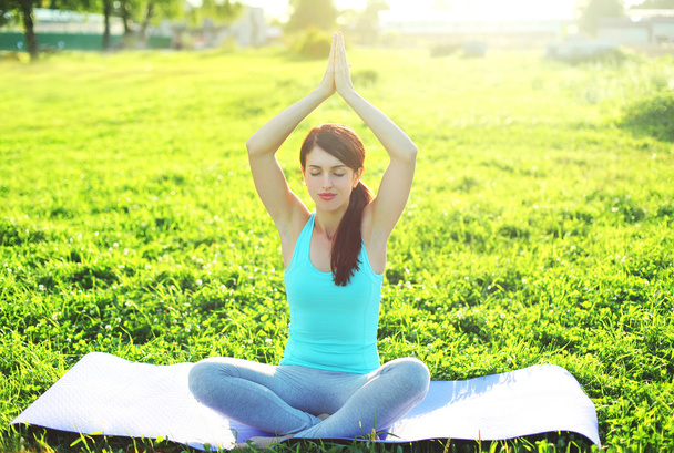 Yoga girl meditates sitting on grass pose lotus in summer day - Foto, immagini