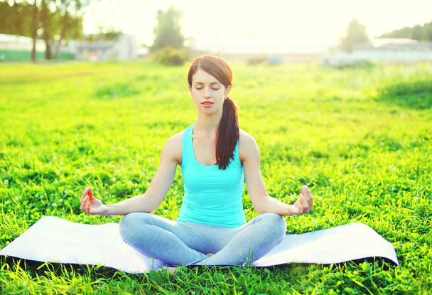Yoga woman meditates on grass pose lotus in sunny day - Foto, afbeelding