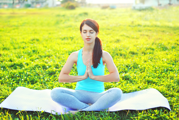 Йога женщина медитирует сидя на траве поза лотос в летний день
 - Фото, изображение